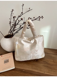 Détail du sac en satin blanc avec motif jacquard brocart et pompon en perles de jade