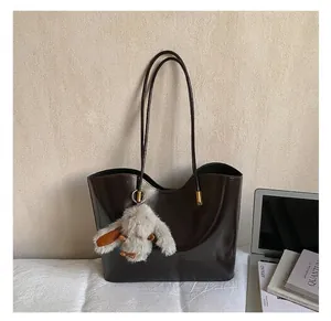 Gros plan sur la texture brillante du cabas en cuir avec breloque lapin en peluche