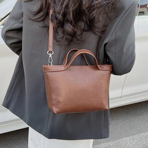 Outdoor street style view of a brown large tote bag with silver hardware on a model