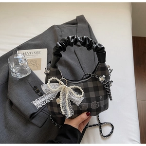 Detail of checkered handbag with pleated handle, pearl lace bow, and chain strap