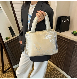 Détail du sac cabas en satin crème avec broderie florale blanche et finitions soignées