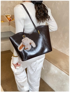 Gros plan d'un grand sac cabas marron en cuir avec charme lapin en peluche doux