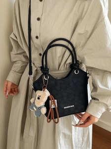 Black leather bucket bag with teddy bear charm and MIAOSHE BAGS logo on the front