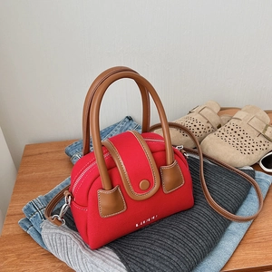 Detailed top view of a red canvas mini Boston bag with brown leather handles on denim cloth