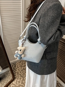 Light blue faux leather bucket bag with cute bear charm shown on model shoulder