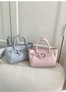 Detail of pink and blue faux leather handbags with lychee grain and buckle on sofa