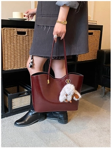 Détail du sac cabas bordeaux en cuir brillant avec un pompon en fausse fourrure douce