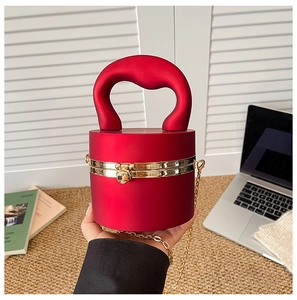 Detail of red cylindrical acrylic bag featuring matte finish and gold ball clasp