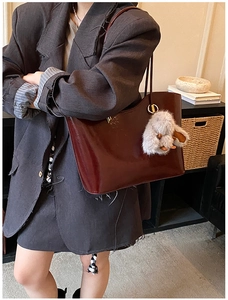 Détail du sac cabas en cuir verni bordeaux avec un charm de lapin en peluche blanc
