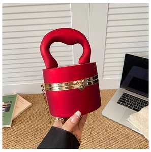 Detail of red cylindrical clutch bag with matte finish and gold spherical clasp