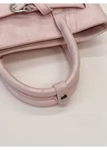 Detail of soft pink bucket bag showing thickened round handle and silver metal buckle