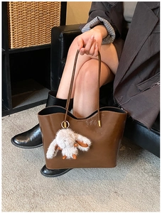 Détail du sac cabas marron brillant avec pendentif lapin et fine bandoulière élégante