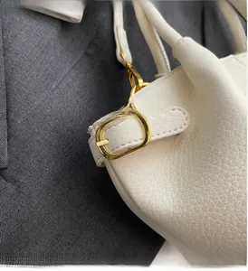 Gros plan sur la texture du cuir litchi blanc et le détail de la boucle en métal doré