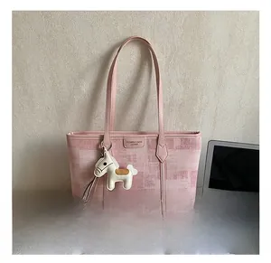 Pink pixel-textured tote bag with leather trim and cute horse charm on desk