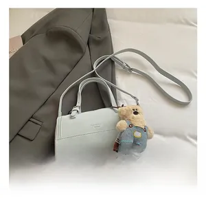 Close-up of light blue leather pillow bag featuring a cute teddy bear plush charm