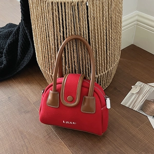 Detail of red canvas crossbody bag with brown leather handles and LIUUU embroidery
