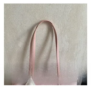 Detail of pink canvas tote showing leather handle stitching and metal hardware accents