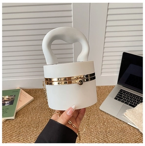 Detail of white cylindrical handbag with thick ring handle and gold metal lock clasp