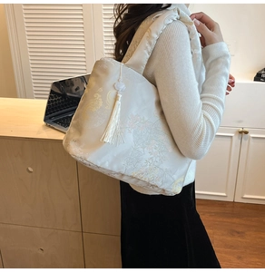 Détail d'un sac cabas en jacquard blanc avec broderie chinoise et pompon décoratif