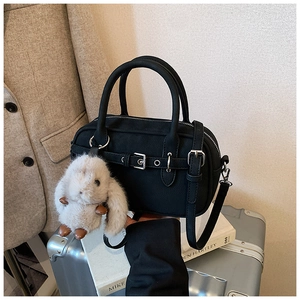 Close-up of black Boston handbag with matte finish and white plush rabbit charm