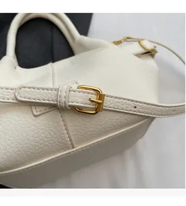 Détail macro du cuir grainé blanc crème avec boucle métallique dorée ajustable
