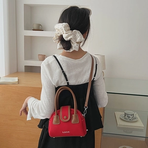 Detailed view of red canvas small square bag with brown leather handles and LIUUU logo