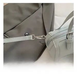 Detail view of premium silver metal hooks on light blue textured leather crossbody bag