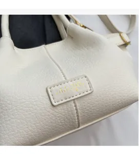 Gros plan du sac cabas blanc en cuir grainé avec logo doré et détails métalliques