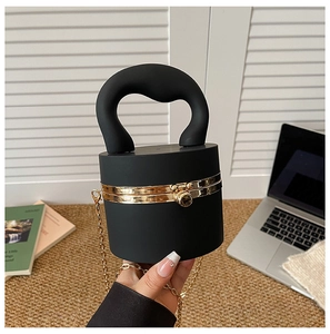 Detail of minimalist black cylindrical bag with large handle and gold ball clasp lock