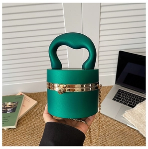 Macro view of dark green cylindrical acrylic clutch with golden spherical clasp