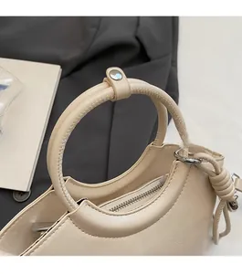 Détail du sac seau crème montrant la fermeture éclair en métal et la poignée ronde