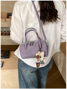 Detail of purple Boston-style pillow bag with plush bear charm and suede texture fabric