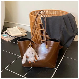 Détail d'un grand sac fourre-tout marron brillant avec un joli pendentif lapin en peluche