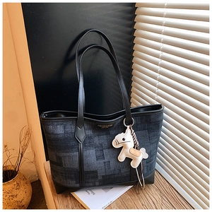 Detailed view of gray checkered tote bag with black leather trim and white horse charm