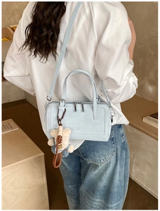 Detail of light blue leather Boston bag with plush bear charm and adjustable strap