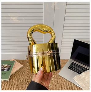 Macro shot of glossy gold acrylic cylinder clutch showing the mirror-like finish and chain