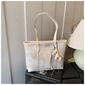 Detail of canvas tote bag featuring premium leather trim and white horse charm accessory