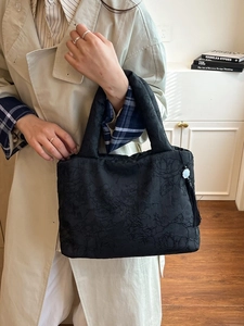 Sac cabas élégant en velours noir avec pompon assorti avec un trench-coat classique