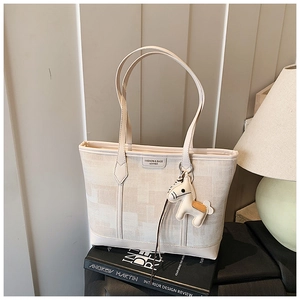 Detail of off-white fabric tote bag with leather trim and decorative pony charm
