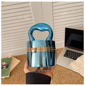 Detail of chrome blue cylindrical clutch bag with gold push-lock and metal chain
