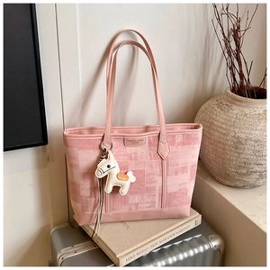 Pink canvas tote bag detail with textured check pattern and white horse charm accessory