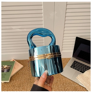Detail of blue acrylic cylindrical clutch with chunky handle and gold chain strap