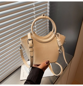 Close-up of cream bucket bag showing 'NO FILTER' embossing and silver heart charm