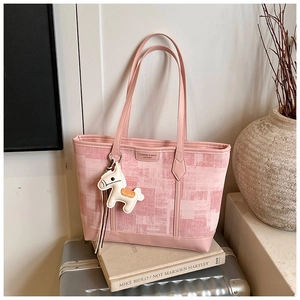 Pink canvas tote bag with leather patchwork and cute pony charm on a silver suitcase