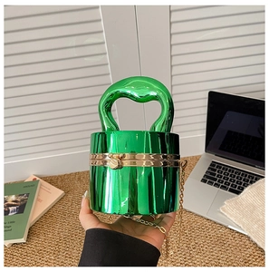 Detail of glossy green acrylic cylindrical clutch with gold metal chain and round snap