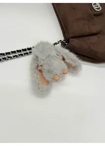 Detailansicht eines grauen Plüschhasen-Anhängers mit Silberkette an Handtasche