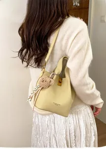 Détail du sac seau jaune crème avec fermoir doré et un joli petit ours en peluche