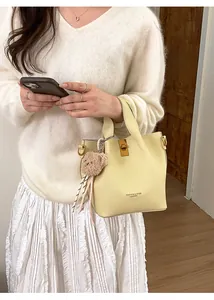 Détail du sac seau jaune clair avec pendentif ours et fermoir rotatif doré élégant
