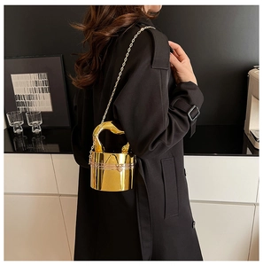 Detailed shot of a gold cylindrical acrylic evening clutch with an ornate handle