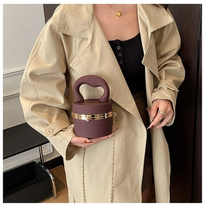 Deep red cylindrical bucket bag with matte texture and gold chain strap detail